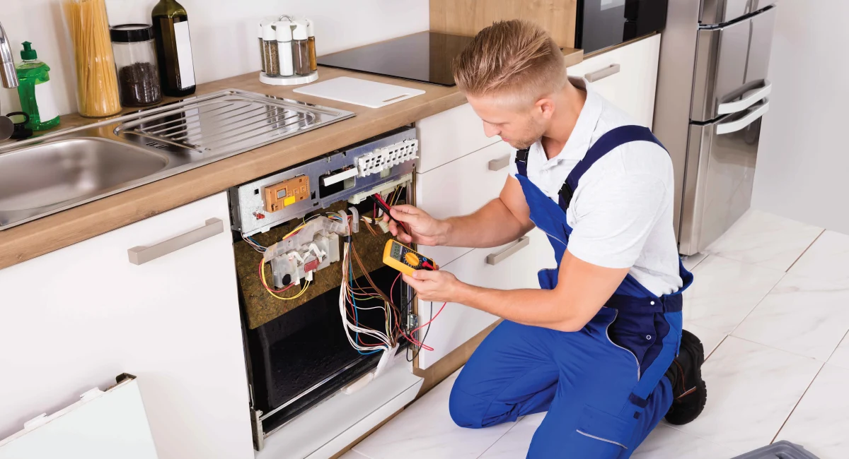 Technician testing an exposed dishwasher control panel with a multimeter