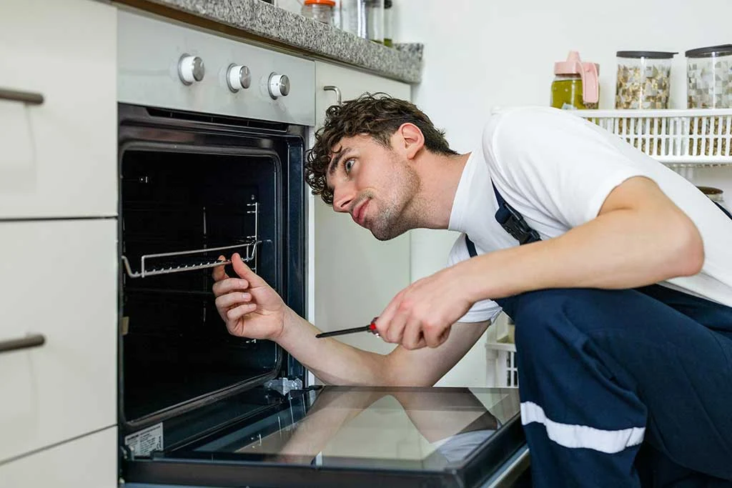 Technician inspecting the interior of an open built-in oven