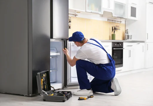 Technician servicing the lower compartment of a refrigerator-freezer