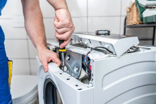 Close-up of a technician repairing the exposed top control area of a washing machine