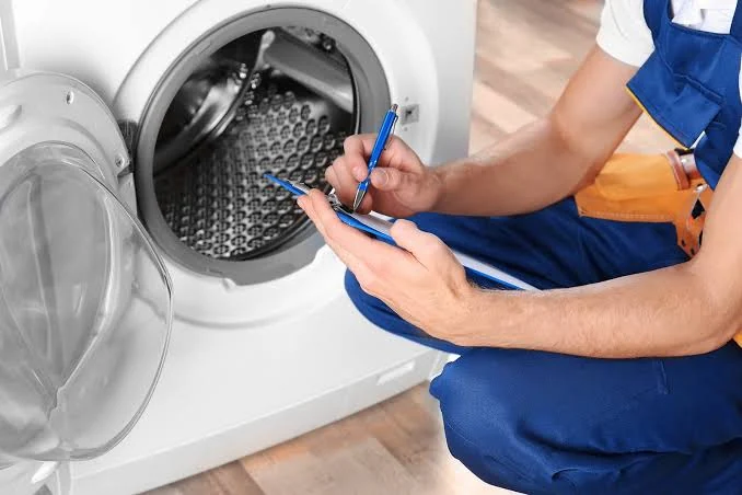 Technician taking notes beside an open front-loading washing machine